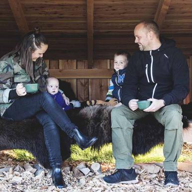 Mother, father and two small children relax on a bison hide in a large shelter