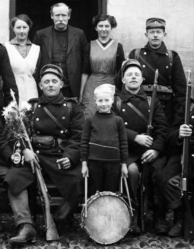 A group of soldiers with rifles and a boy with a drum