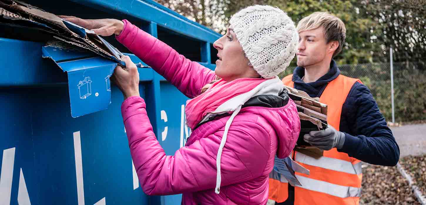 A woman puts cardboard in the cardboard container