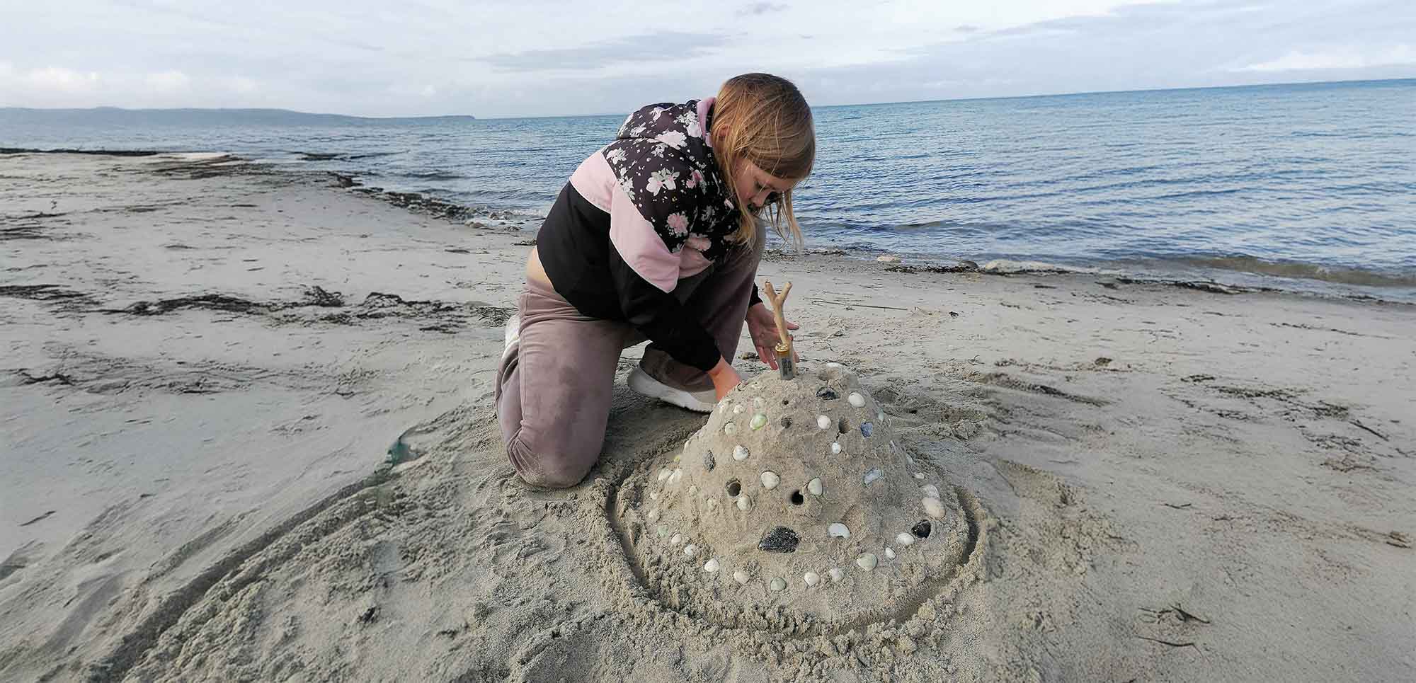 Efterår - pige i varmt tøj bygger flot sandslot på Flyvesandet Strand