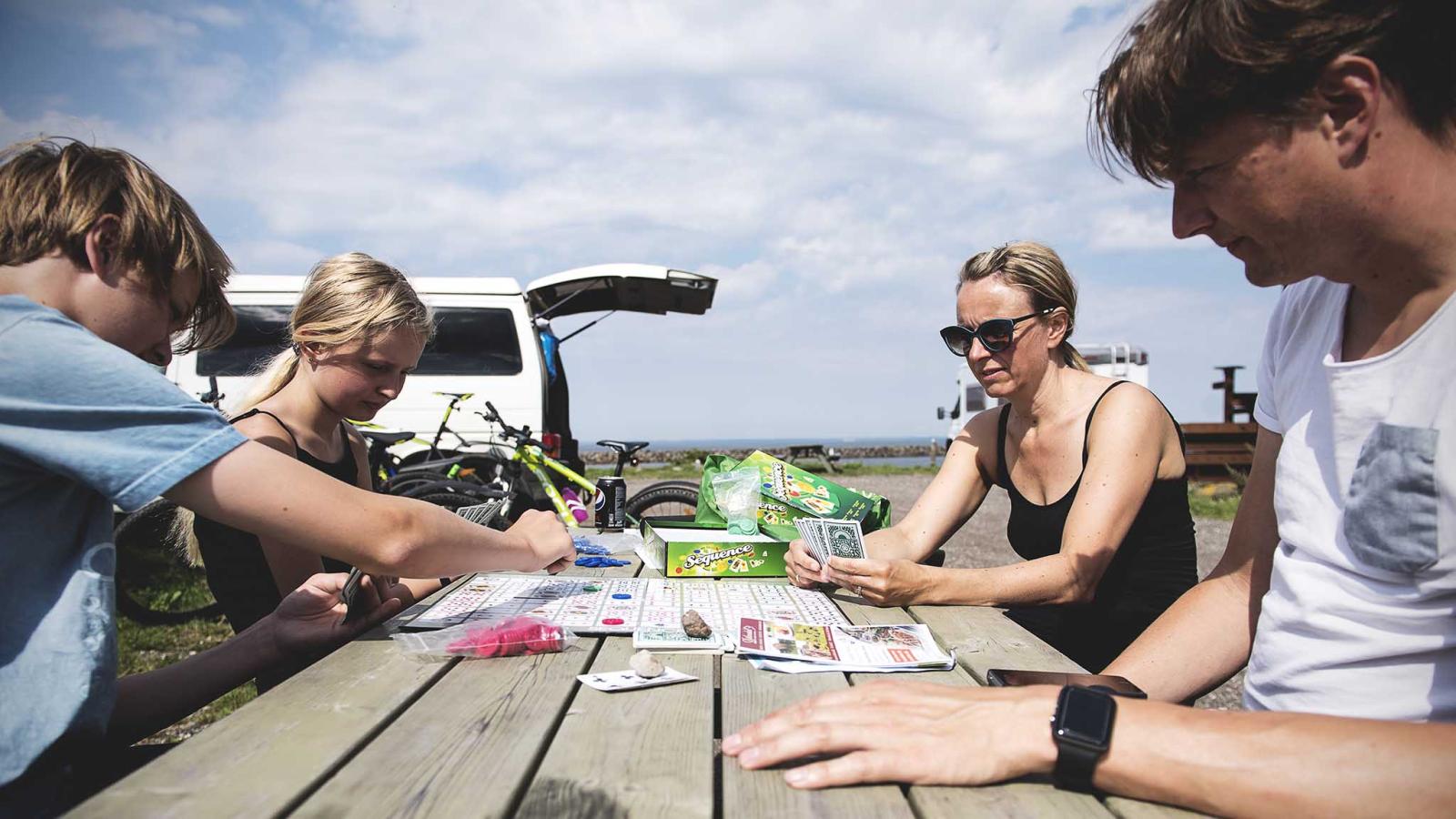 Familie spiller kort ved autocamper