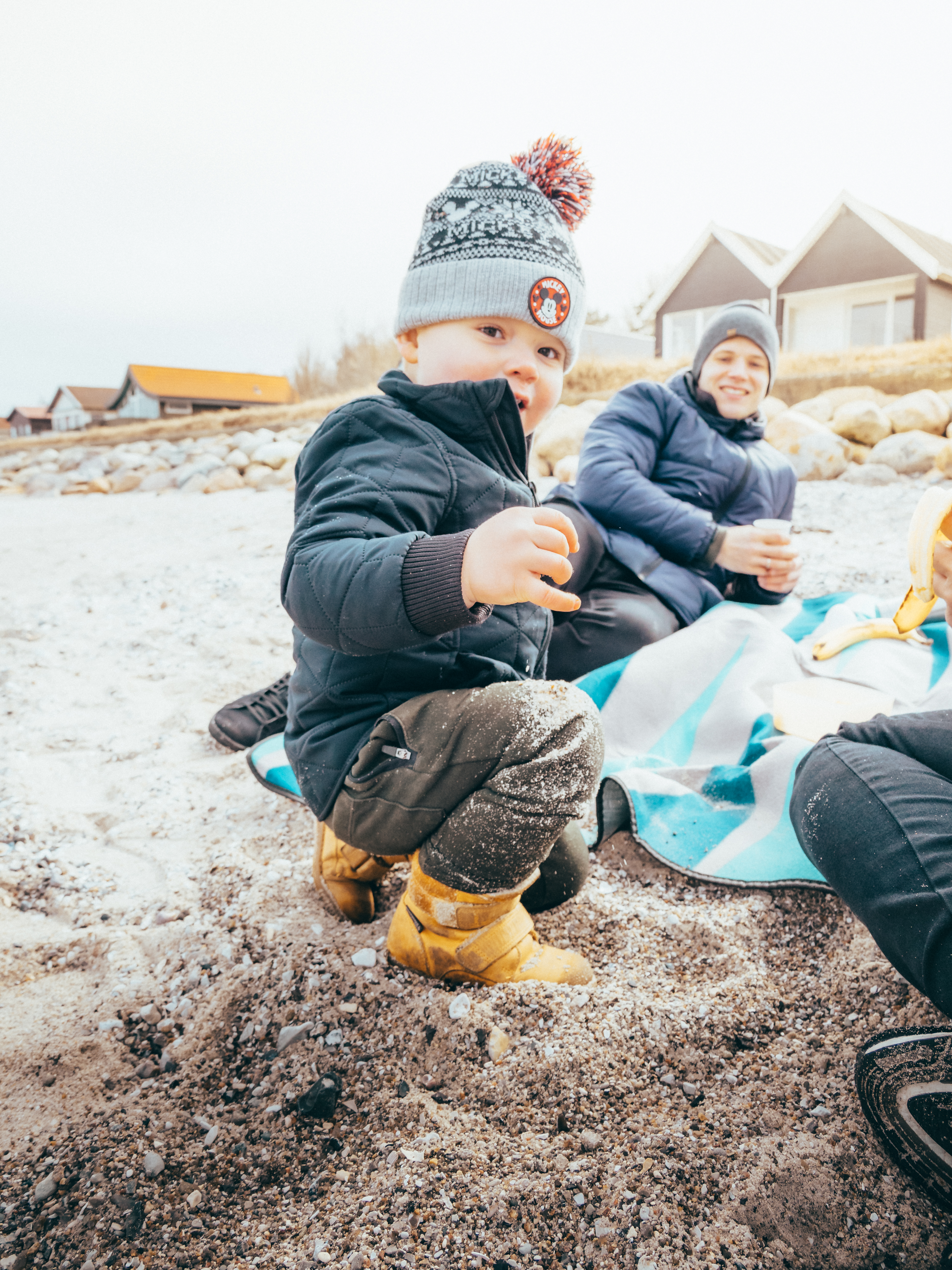 Barn holder ved noget på en strand i vintertid