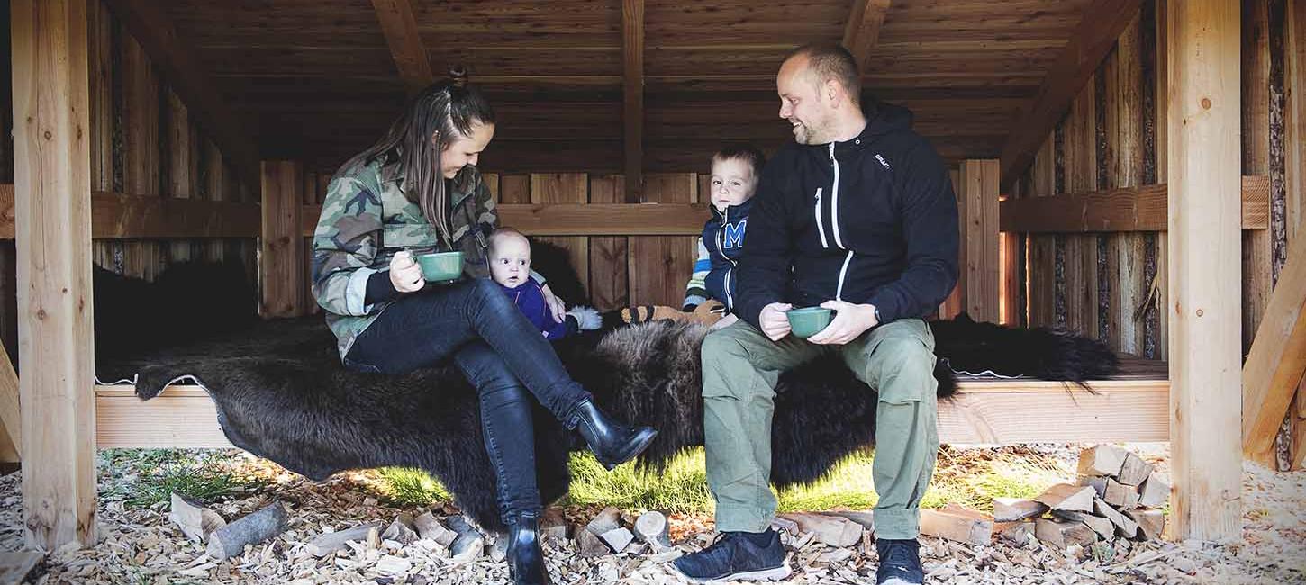 Mother, father and two small children relax on a bison hide in a large shelter