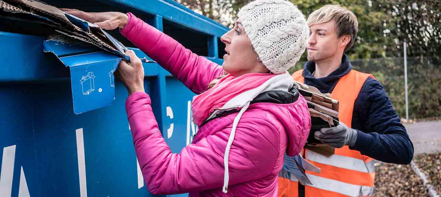 A woman puts cardboard in the cardboard container