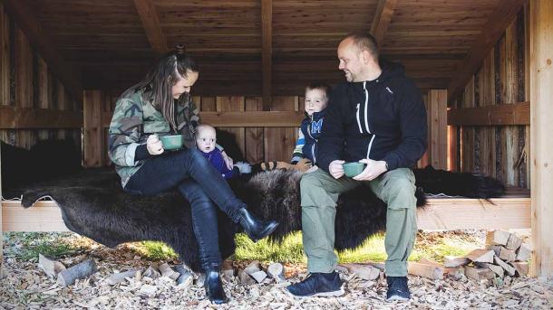 Mother, father and two small children relax on a bison hide in a large shelter