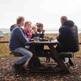 Familie holder picnic på Gyldensteen Strand i efteråret