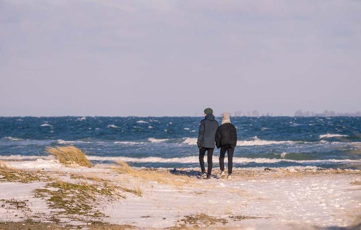 A couple goes for a walk on the beach at Flyvesandet in winter